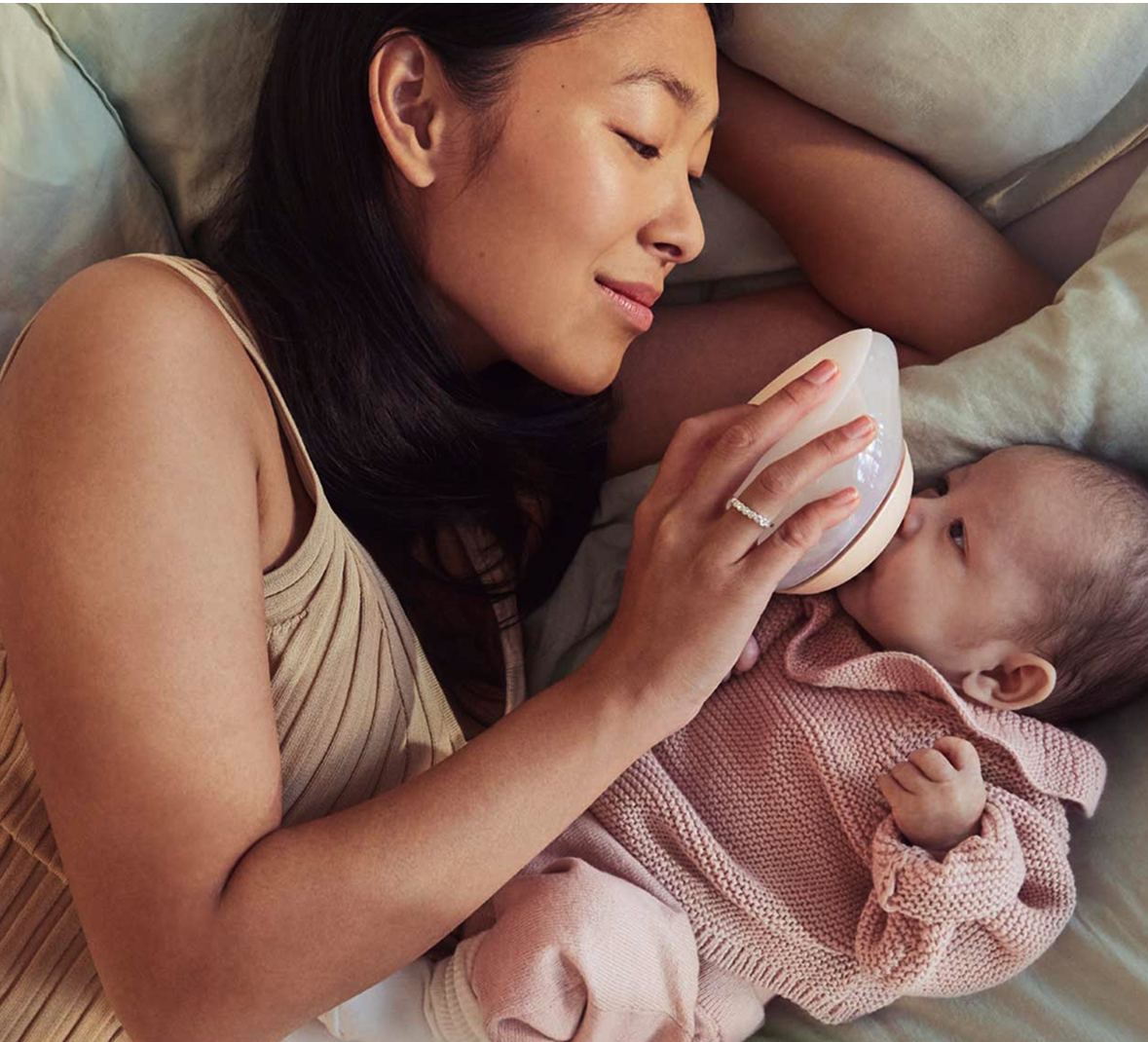Mother feeding baby with a baby bottle shaped like a breast