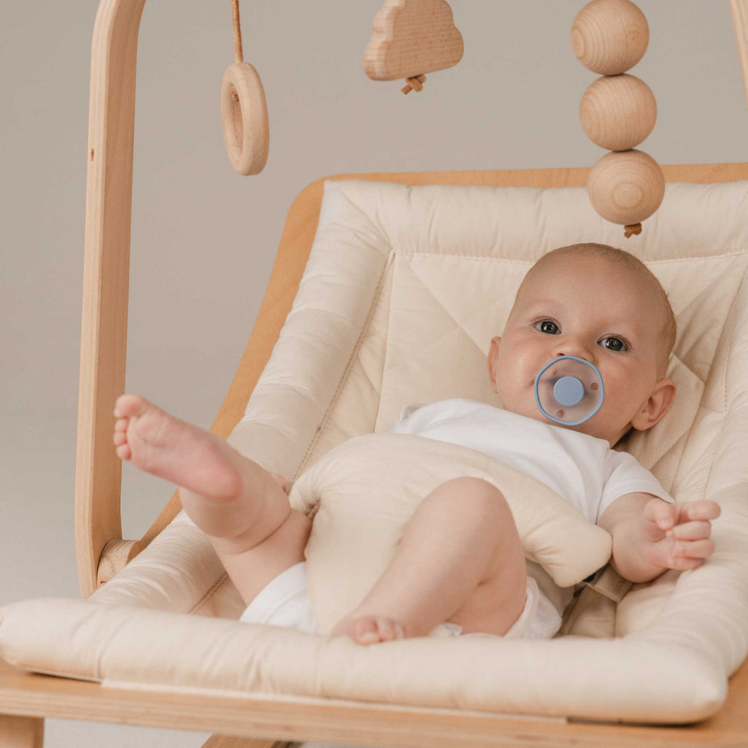 Baby in baby rocker with Blu Emulait Pacifier